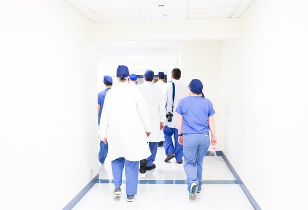 Pressure injury treatment. Nurses in scrubs walking down white hospital corridor. 